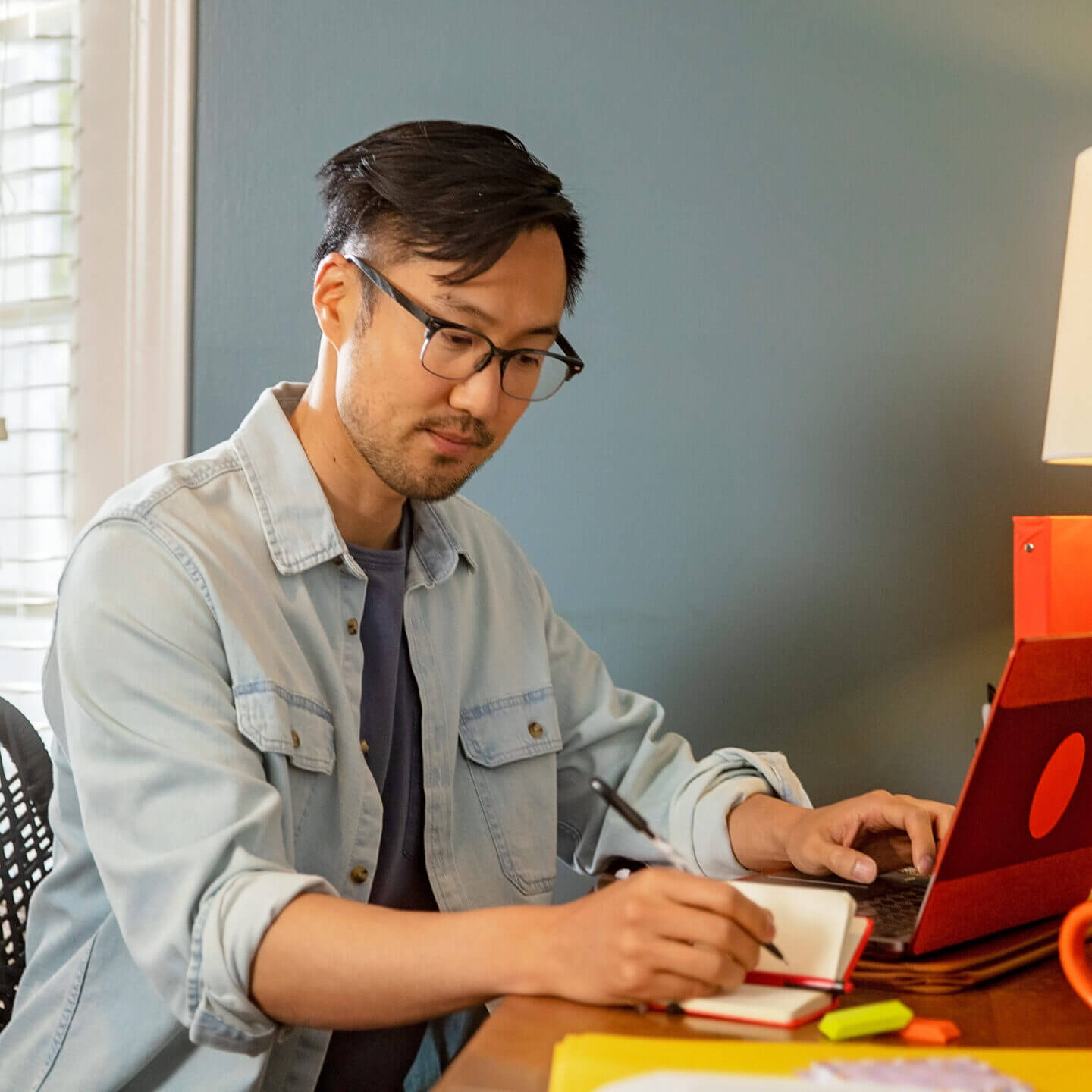 Volunteer working and writing in a notebook and typing on the computer