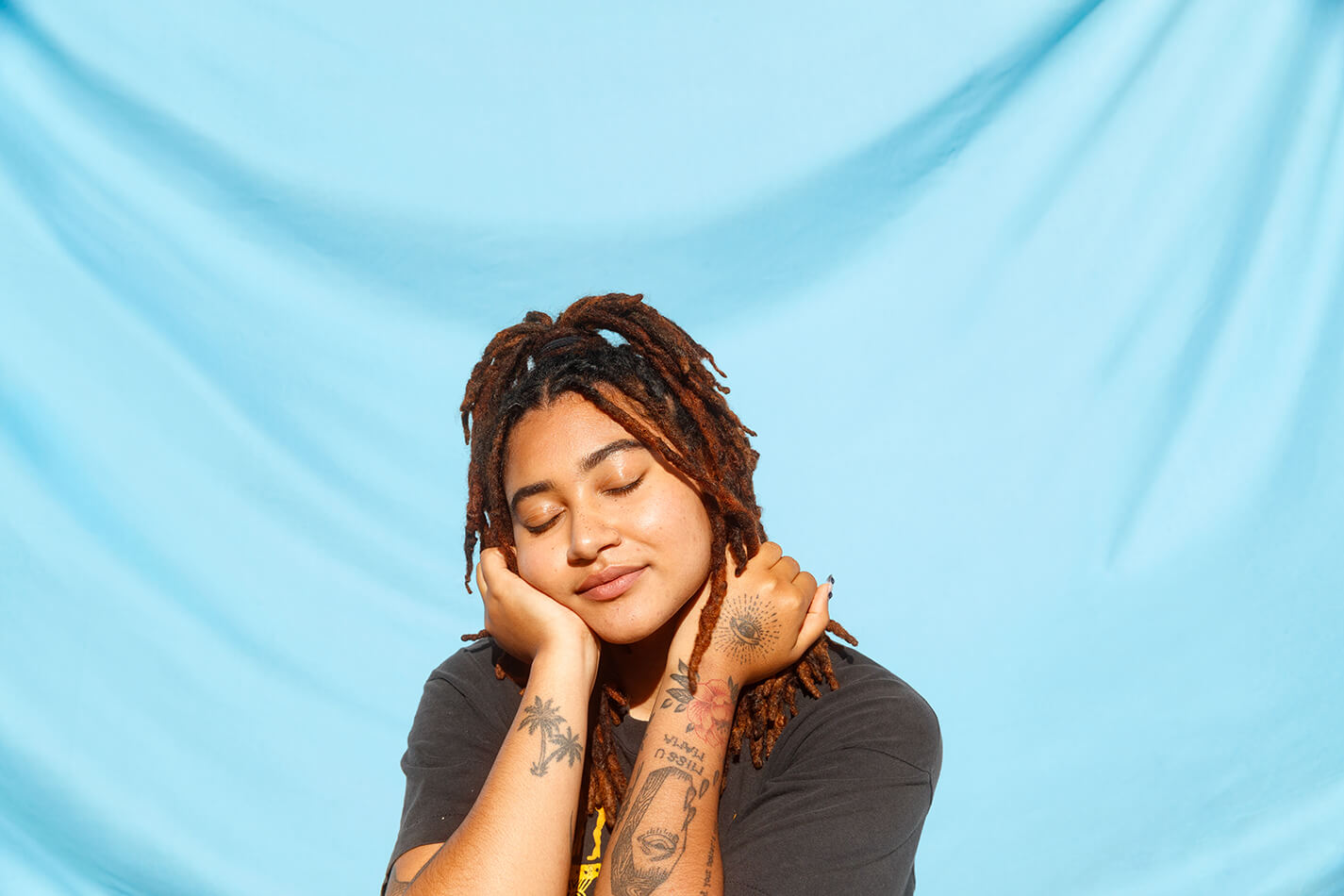 LGBTQ youth resting their head on their hands with eyes closed