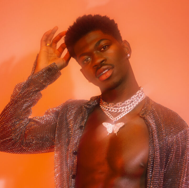 Lil Nas X posing against an orange background