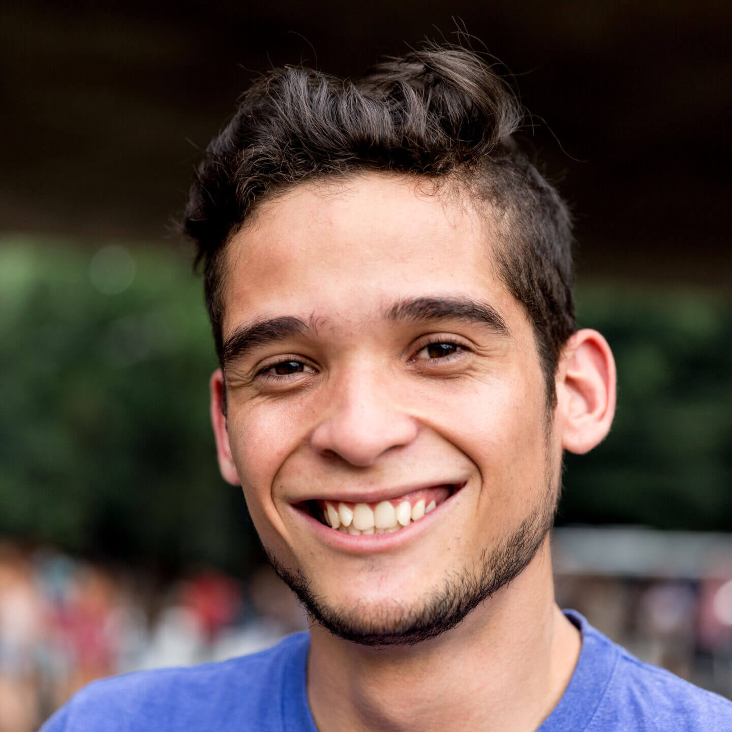 A person in a purple t-shirt outside smiling.