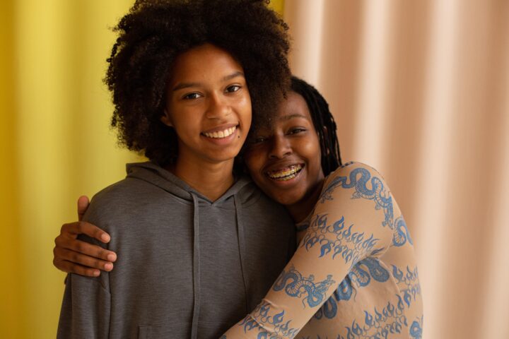 Two BIPOC youth embracing and smiling