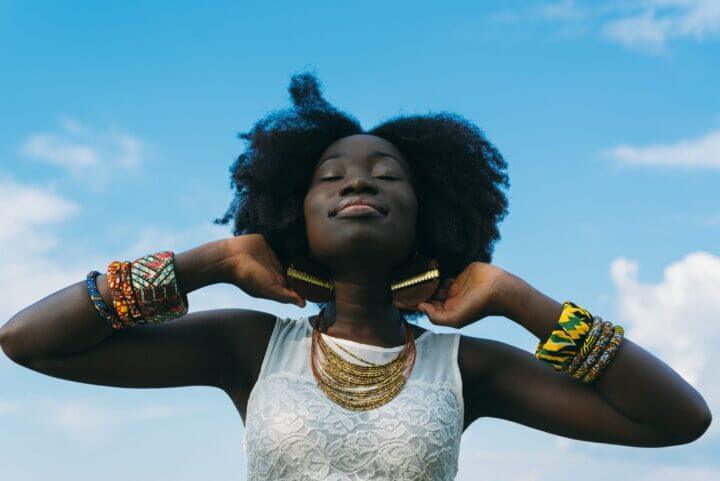 BIPOC person smiling against a background of a blue sky