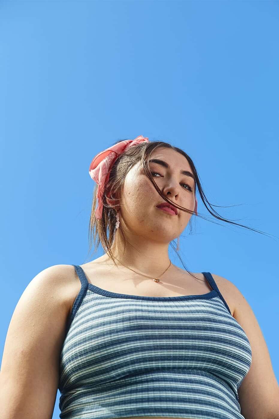 Portrait of an LGBTQ young person against a blue sky