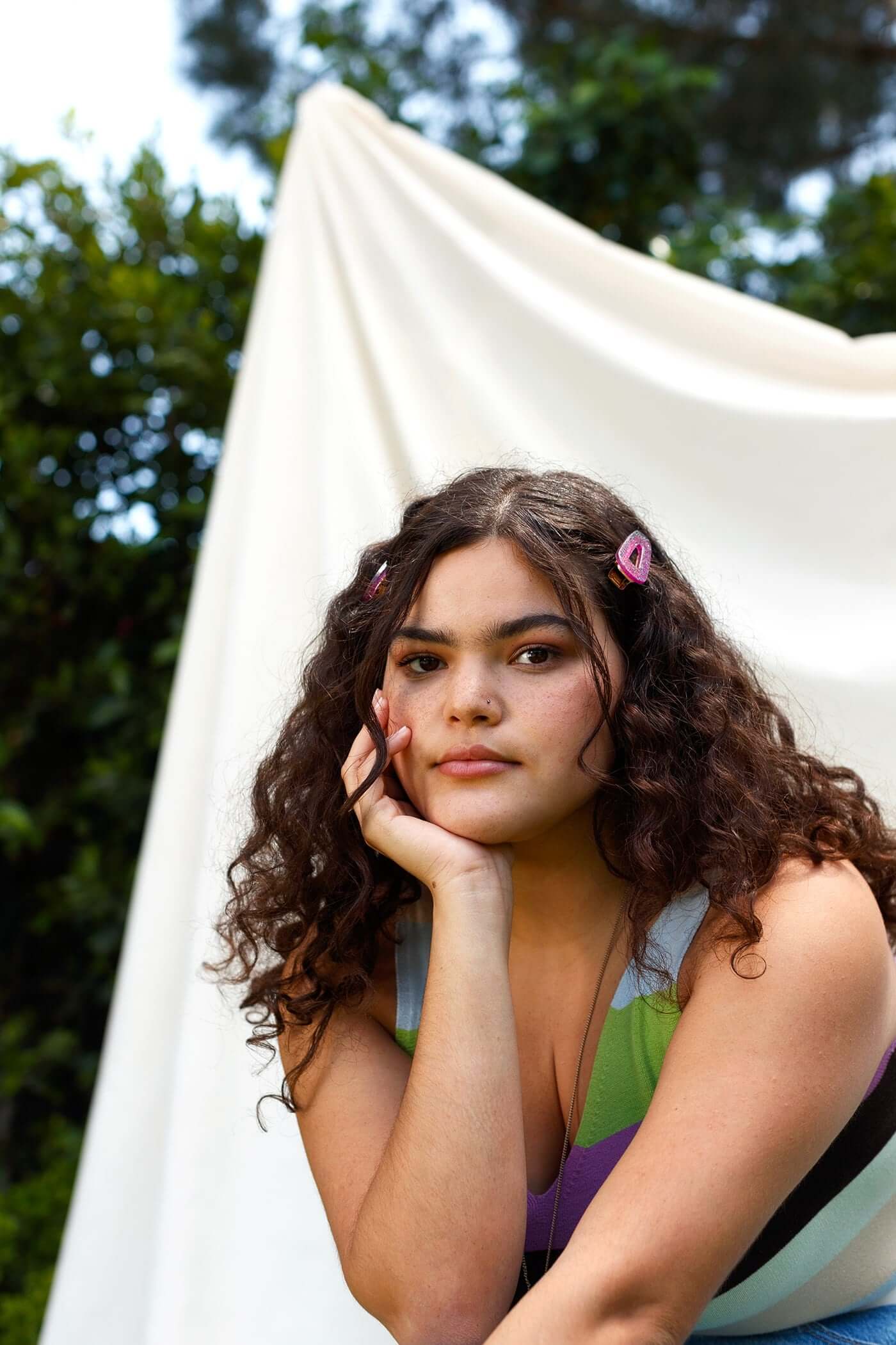 Portrait of a LGBTQ young person wearing a striped shirt with a white backdrop