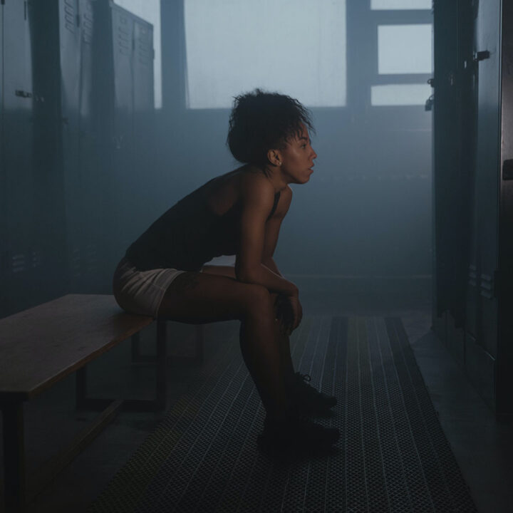 Person sitting alone on bench in locker room