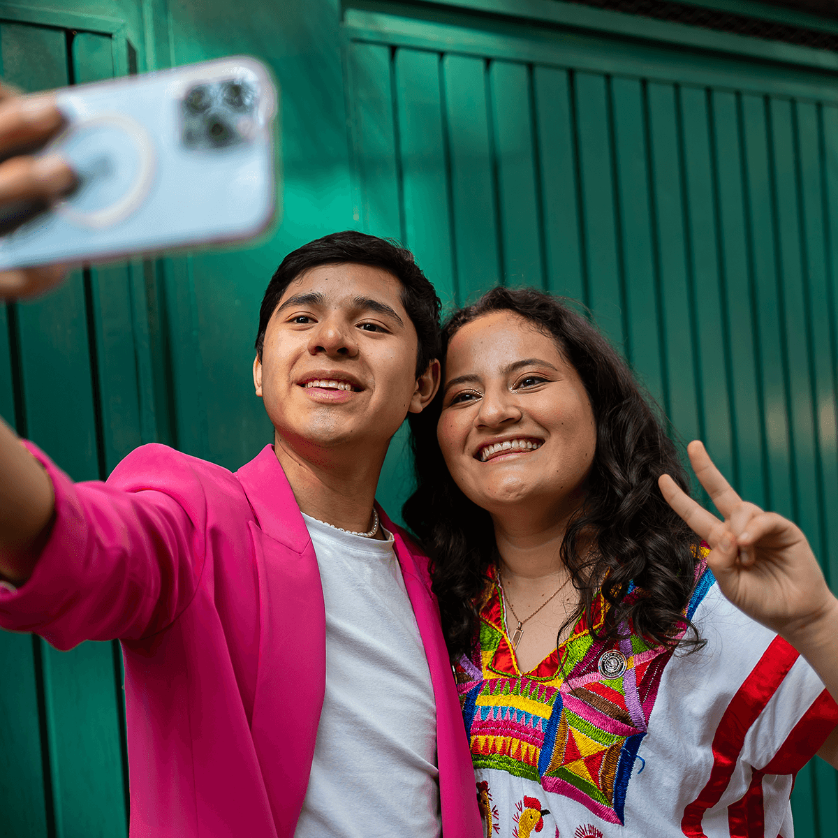 Two people in colorful outfits posing while filming themselves with a smartphone.
