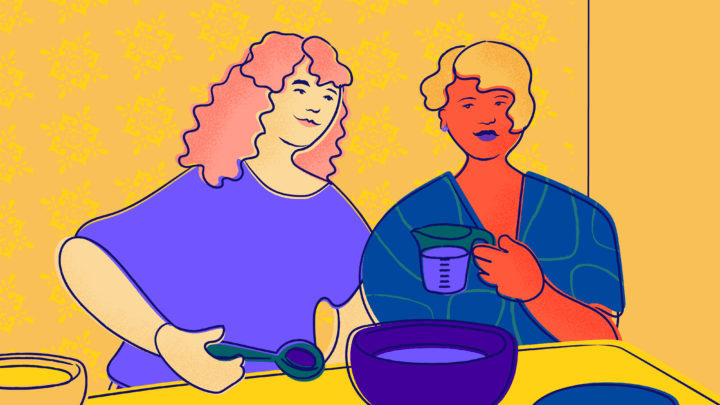 Two friends hold a measuring cup and prepare a recipe in front of yellow wallpaper.