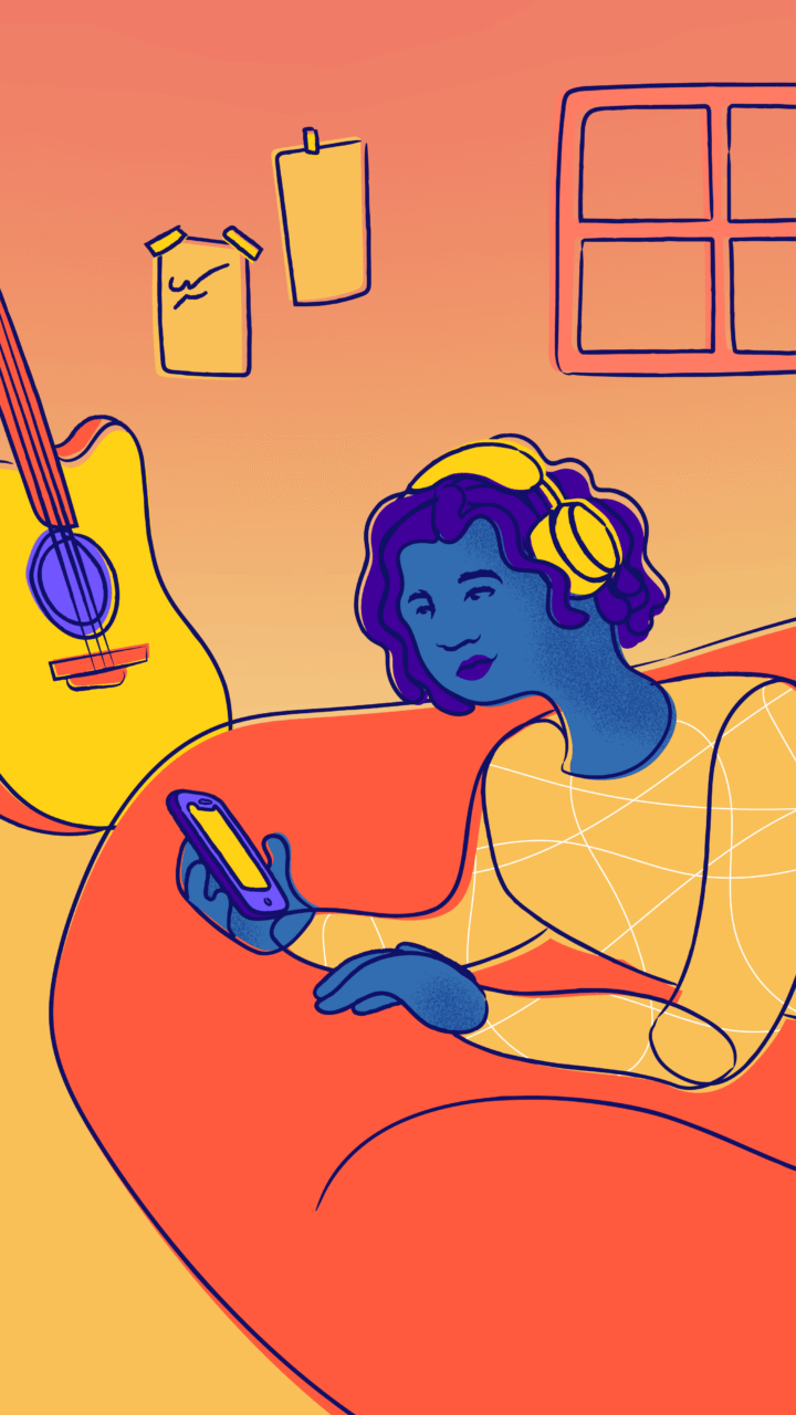 A young person texts on their bed with headphones on, next to a guitar and a window.